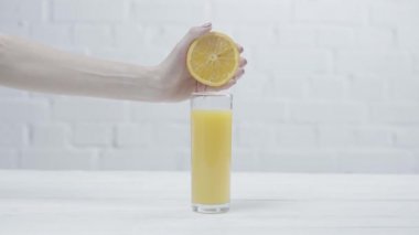 portakal suyu bardağının yanında portakal sıkan kadının kırpılmış görünümü 