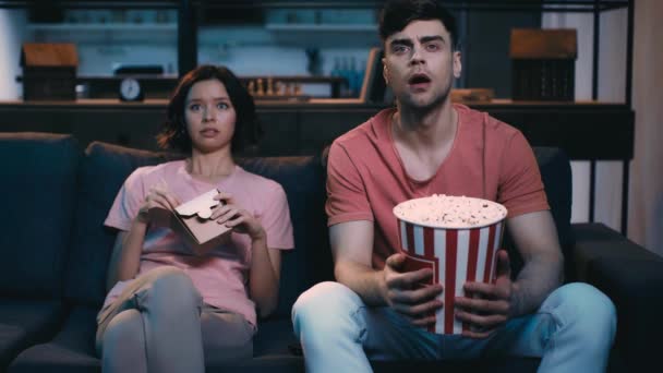 Chocado Homem Mulher Assistindo Enquanto Sentado Sofá Tendo Lanches Olhando — Vídeo de Stock