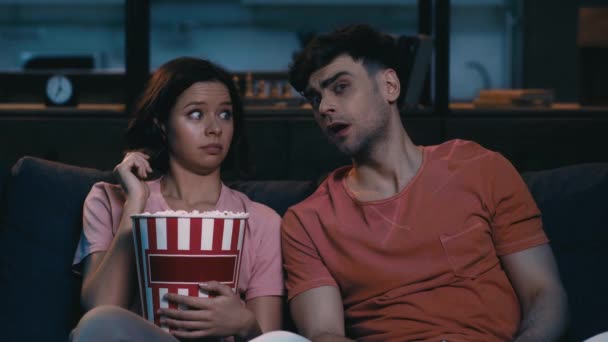 Schockierte Junge Mann Und Frau Vor Dem Fernseher Essen Popcorn — Stockvideo