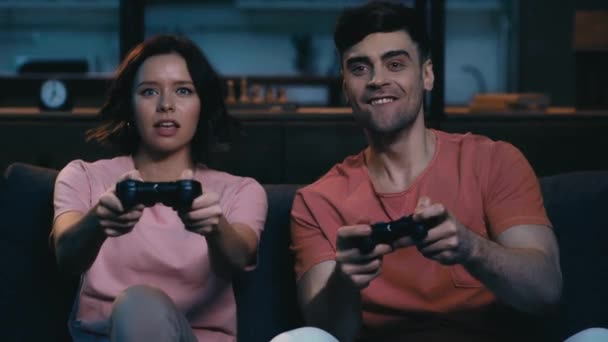 キエフ ウクライナ 2019 ジョイスティックでビデオゲームをプレイ興奮若い男女 勝者のジェスチャーを示し 動揺した女の子を見て男 — ストック動画