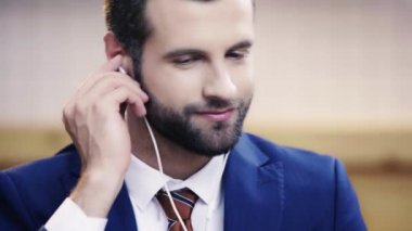 takım elbiseli yakışıklı ve esmer adam müzik dinlerken, kahve içme ve kafede gülümseyen 