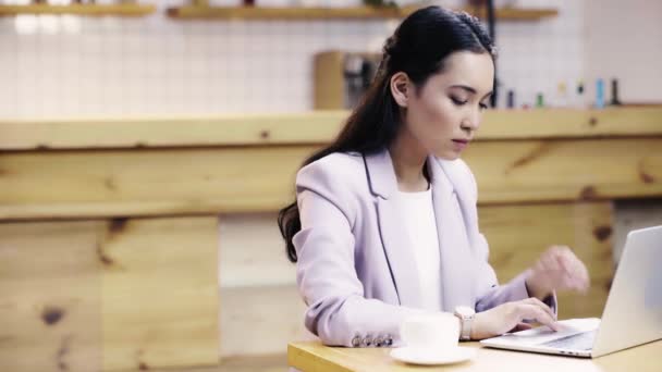 カフェでラップトップにタイピングスーツで焦点を当てた かなりアジアのビジネスウーマン — ストック動画