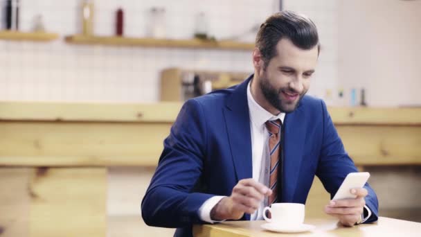 英俊和微笑的商人在西装喝咖啡和使用智能手机 — 图库视频影像