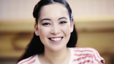 çekici, esmer, asyalı kadın kameraya bakıyor ve kafede gülümsüyor 