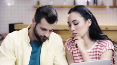 yakışıklı adam asyalı kadın ile belgeleri tartışıyor, dizüstü ekran bakarak ve kafede akıllı telefon konuşuyor 