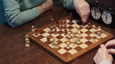 satranç oynayan ve masada satranç saati üzerine düğmeye basarak iki üst düzey erkek kısmi görünümü