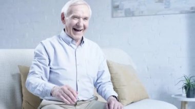 kanepede oturan ve oturma odasında arkadaşı ile el sıkışma gömlek gülen kıdemli adam