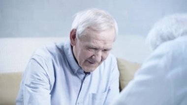 mavi gömlek neşeli yaşlı adam arkadaş bakarak ve oturma odasında gülüyor