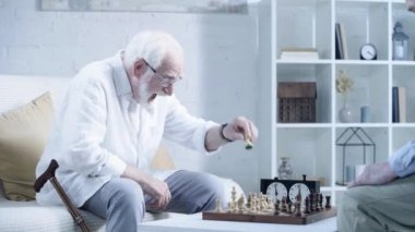 satranç oynayan gözlüklü sakallı yaşlı adam, ellerini ovuşturarak, gülerek ve rakip ile el sıkışma