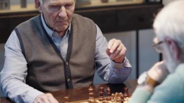 satranç oynayan ve satranç saati üzerinde düğmeye basarak iki üst düzey erkek kırpılmış görünümü