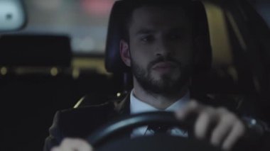 yakışıklı sakallı adam saat bakarak seçici odak, direksiyon u tutan, akıllı telefon alarak ve araba sürerken konuşurken