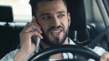 yakışıklı adam akıllı telefon konuşurken seçici odak, gülümseyen ve direksiyon tutan 