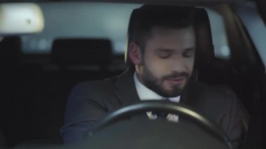 yakışıklı adam emniyet kemeri bağlama ve arabada otururken gülümseyen raf odak 