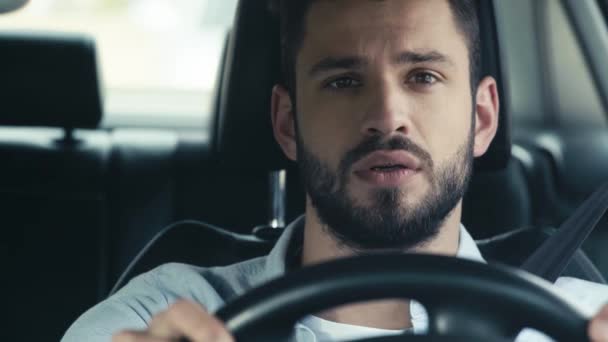 車の中でステアリングホイールを保持するハンサムなひげの男の選択的な焦点 — ストック動画