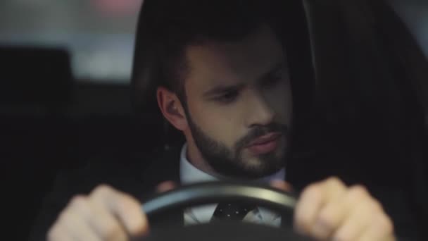 車を運転しながらステアリングホイールを保持するスーツでハンサムなひげの男の選択的な焦点 — ストック動画