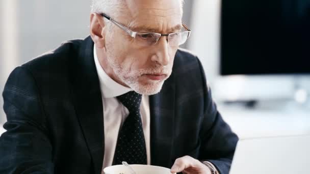 オフィスでおいしいサラダを食べるメガネでハンサムなビジネスマンのクローズアップ — ストック動画