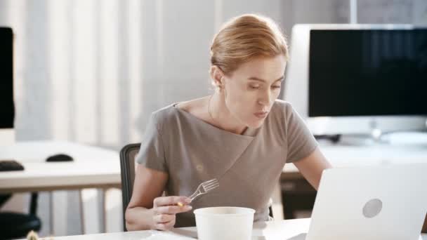 美丽的女商人使用笔记本电脑 采取塑料叉和在办公室吃沙拉 — 图库视频影像