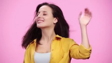 güzel kız kafa sallayarak saç üfleme hava yavaş hareket ve pembe üzerinde Izole gülümseyen