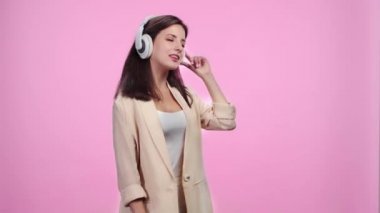 akıllı telefon dinleme müzik ve dans ile kulaklıklar güzel gülümseyen kız pembe üzerinde Izole