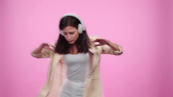 belle fille dans casque écouter de la musique, geste et danse sur rose 