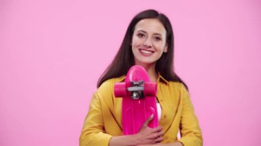 güzel kız ile Penny Board gülümseyen ve görünümlü kamera Izole pembe