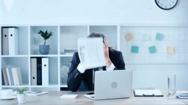 üzgün işadamı Infographics ile kağıtlar atma yavaş hareket ve işyerinde otururken eller ile kafa kapsayan