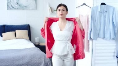 üzgün kadın pembe blazer, beyaz pantolon ve bluz yatak odasında çalışıyor