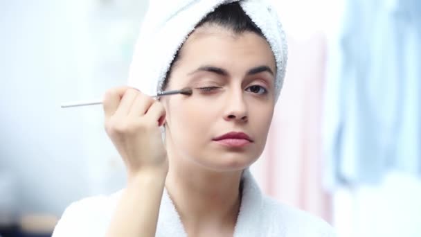 化粧品ブラシでアイシャドウを適用するバスローブで笑顔の女性 — ストック動画