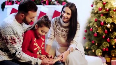 neşeli çocuk anne-baba yakınında santa mektup yazma 