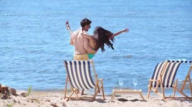 birlikte plajda dinlenirken elleriyle kız arkadaşı tutan mutlu genç adam