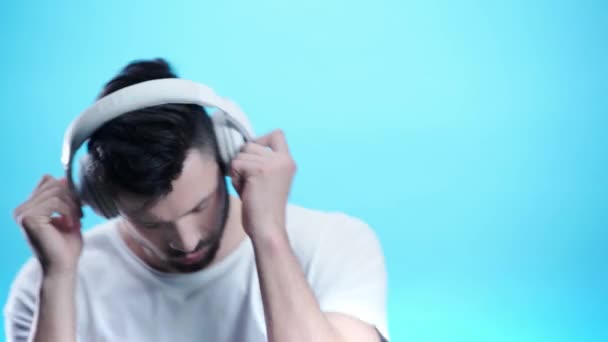 青のヘッドフォンで音楽を聴くハンサムな男 — ストック動画