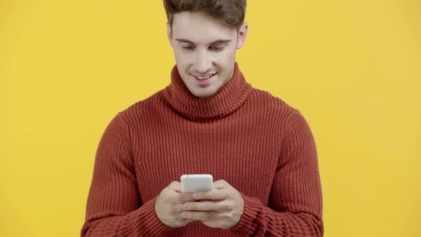 Homem Alegre Camisola Mensagens Texto Smartphone Isolado Amarelo — Vídeo de Stock