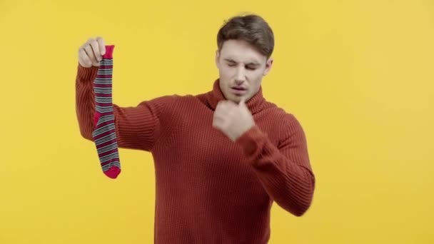 Disgusted Man Sweater Smelling Stinky Sock Isolated Yellow — Stock Video