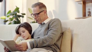 dedesi ve torunu oturma odasında birlikte kitap okuma