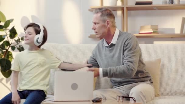 Abuelo Ofreciendo Nieto Leer Libro Mientras Niño Escuchar Música Auriculares — Vídeo de stock