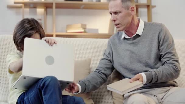 Grandfather Offering Grandson Read Book While Boy Using Laptop — Stock Video