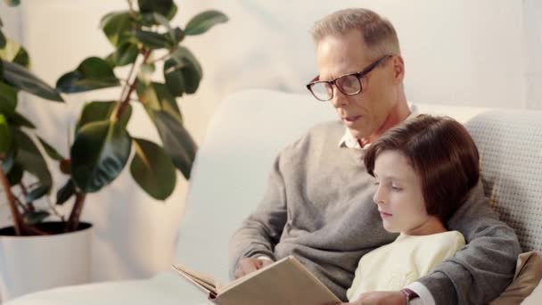 Παππούς Γυαλιά Και Εγγονός Διαβάζοντας Βιβλίο Μαζί Στο Σαλόνι — Αρχείο Βίντεο