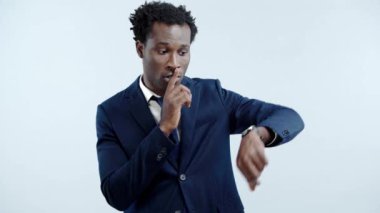 Ciddi bir Afro-Amerikan iş adamı Gri üzerinde izole edilmiş sessizlik işareti gösteriyor.
