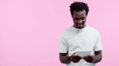 Pozitif Afro-Amerikan adam pembe üzerinde izole dijital tablet gösteriyor