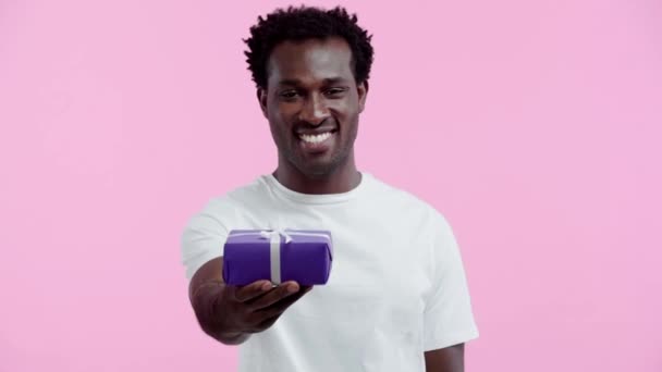 Souriant Homme Afro Américain Présentant Boîte Cadeau Isolé Sur Rose — Video