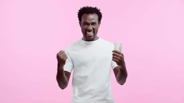アフリカ系アメリカ人男性がピンクに隔離されたドルを持ち — ストック動画