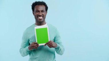 Neşeli Afrikalı Amerikalı adam mavi üzerinde dijital tablet gösteriyor.