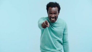 Gülen Afro-Amerikan adam mavi üzerine parmak işareti yapıyor.