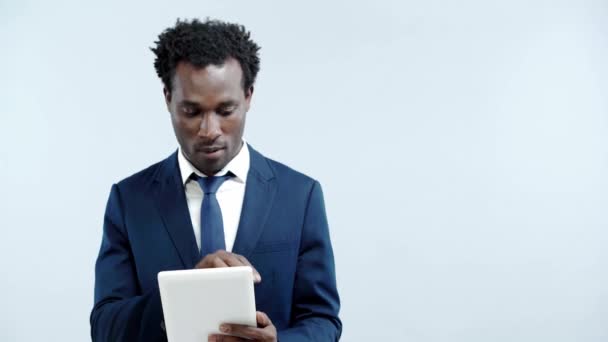 グレーで隔離されたデジタルタブレットを見せるアフリカ系アメリカ人ビジネスマン — ストック動画