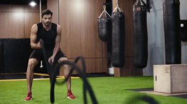 Sakallı adam askılarla çalışıyor. 