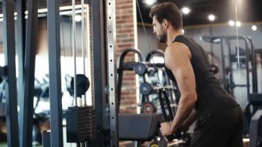 Sakallı sporcu spor salonunda egzersiz yapıyor. 