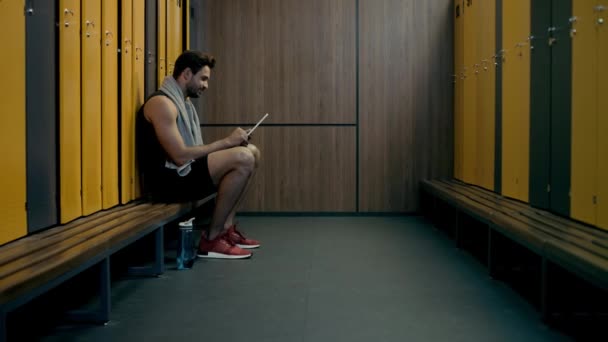 ロッカールームでデジタルタブレットを使う幸せなスポーツマン — ストック動画