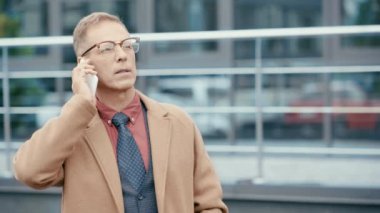 Palto giyen işadamı akıllı telefondan konuşuyor. 
