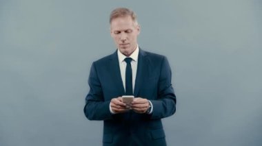 Takım elbiseli işadamı gülümsüyor ve akıllı telefon kullanıyor. 