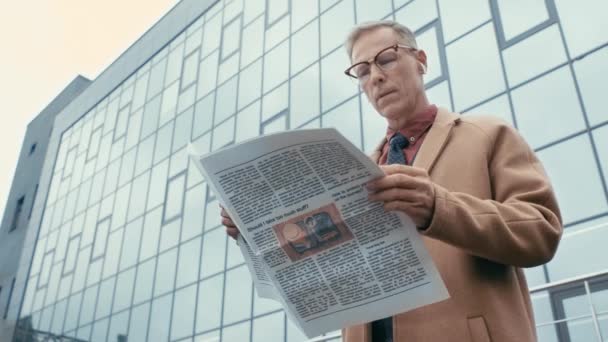low angle view of businessman in coat reading newspaper 